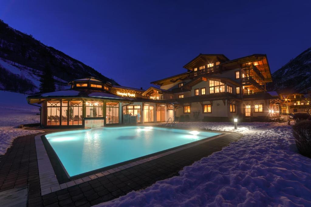 a house with a swimming pool in the snow at night at Feriendorf Ponyhof in Fusch an der Glocknerstraße