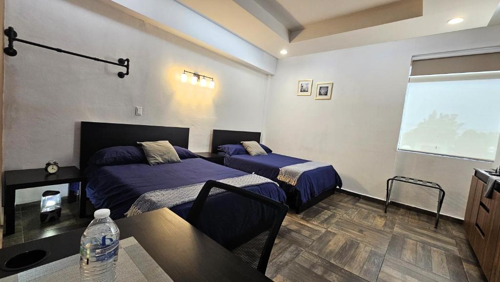 a bedroom with two beds and a table and a window at A30 MAX Suite BLACK MAX Cocina Terraza Companies Work Teams 1-3 PAX in Cuautitlán Izcalli
