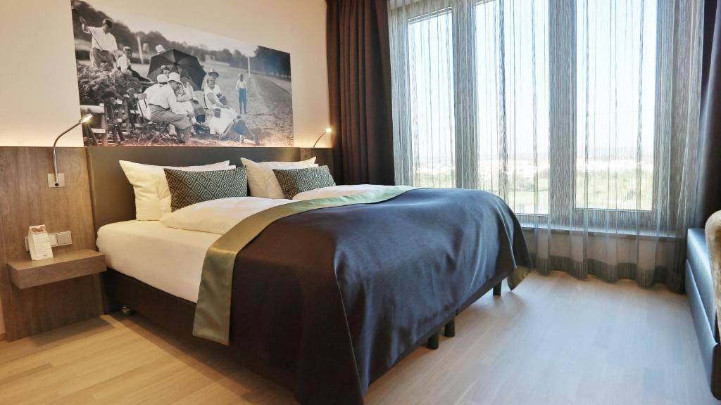 ein Schlafzimmer mit einem Bett und einem großen Fenster in der Unterkunft Hotel TheGreen ehemals Köln11 in Köln
