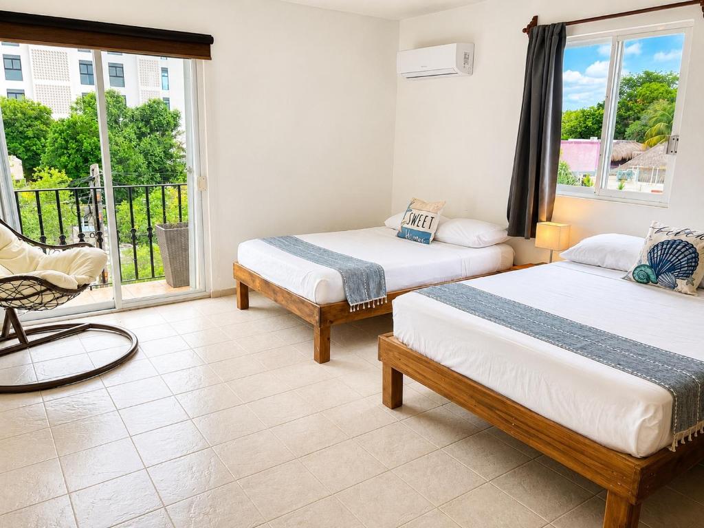 two beds in a room with a window at Aguacatl Cozumel a 3 cuadras del mar in Cozumel