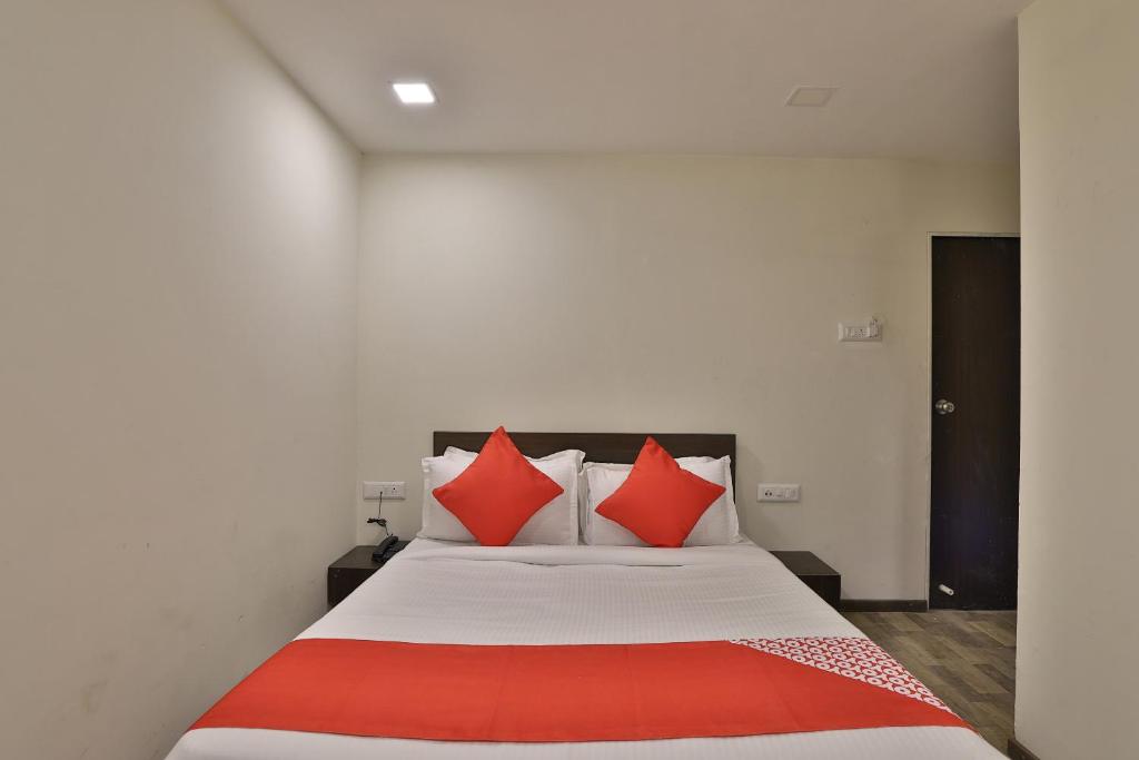 a bedroom with a large bed with red pillows at Hotel O Ripple Mall in Surat