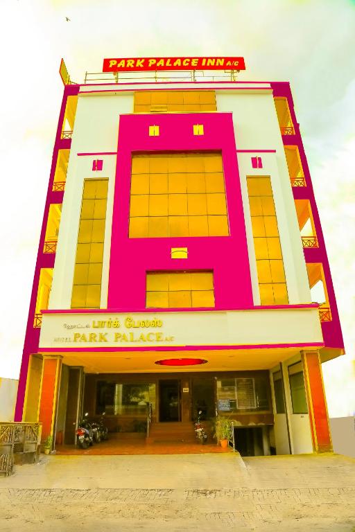 a pink and yellow building with a parking garage at Park Palace Inn in Erode
