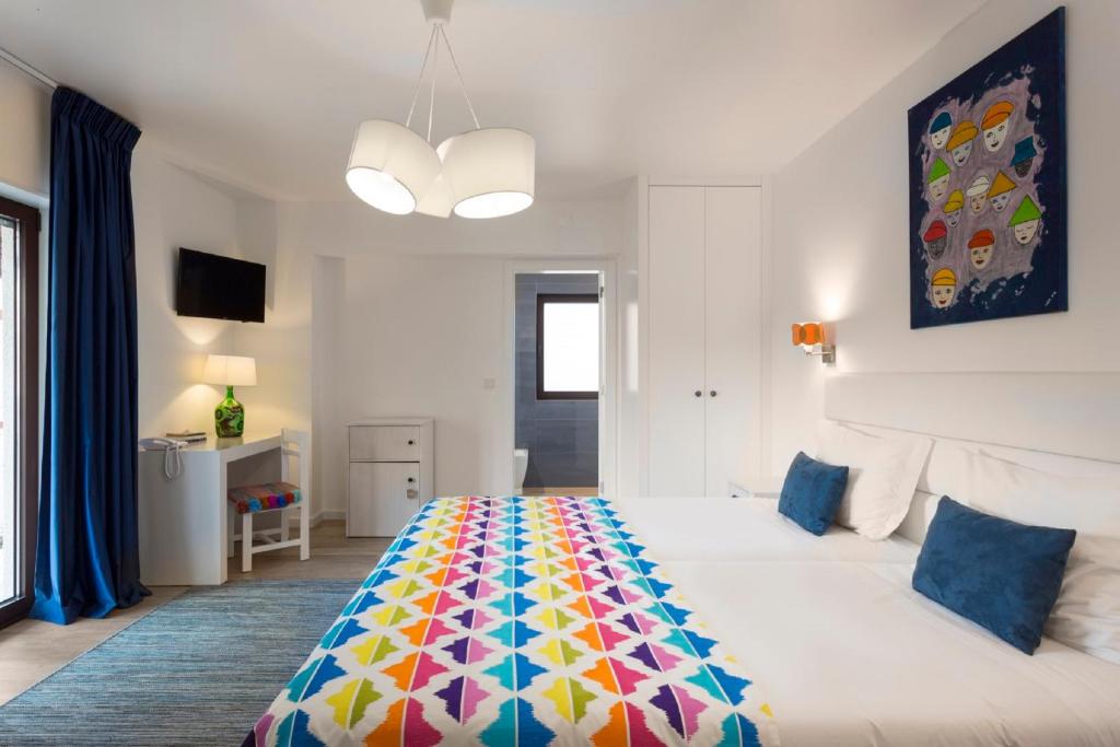 a bedroom with a large bed with a colorful blanket at Boutique Hotel Casa do Outeiro - Arts & Crafts in Batalha