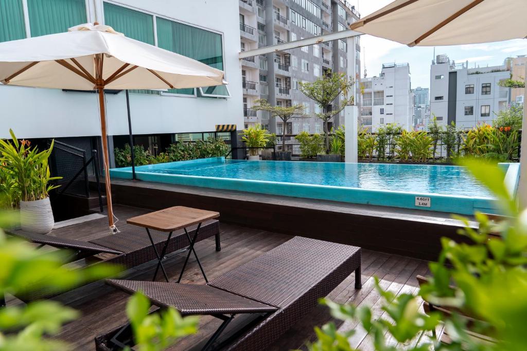 a swimming pool with tables and umbrellas on a building at Monsoon Bassac Hotel in Phnom Penh