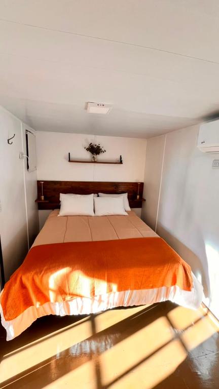 a bedroom with a bed with an orange blanket at Las Cinco Esquinas in Nueve de Julio