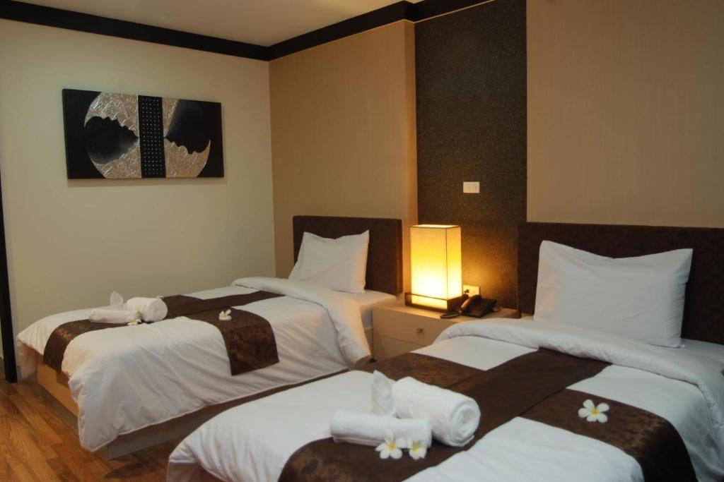 a hotel room with three beds with towels on them at Panatara Chumphon in Chumphon