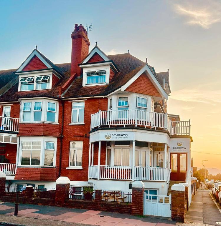 a large red brick house with a white balcony at SmartsWay Hotel & Wellness in Eastbourne