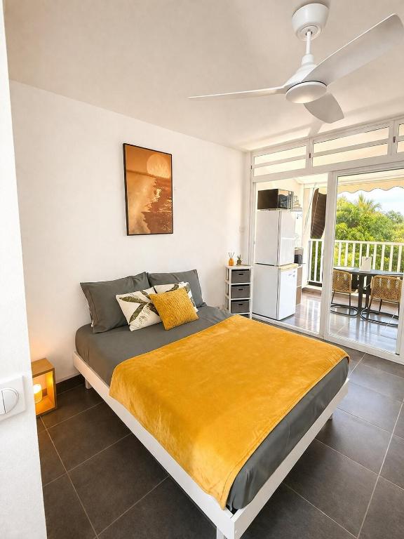 a bedroom with a large bed with a yellow blanket at Soleya Studio in Le Moule