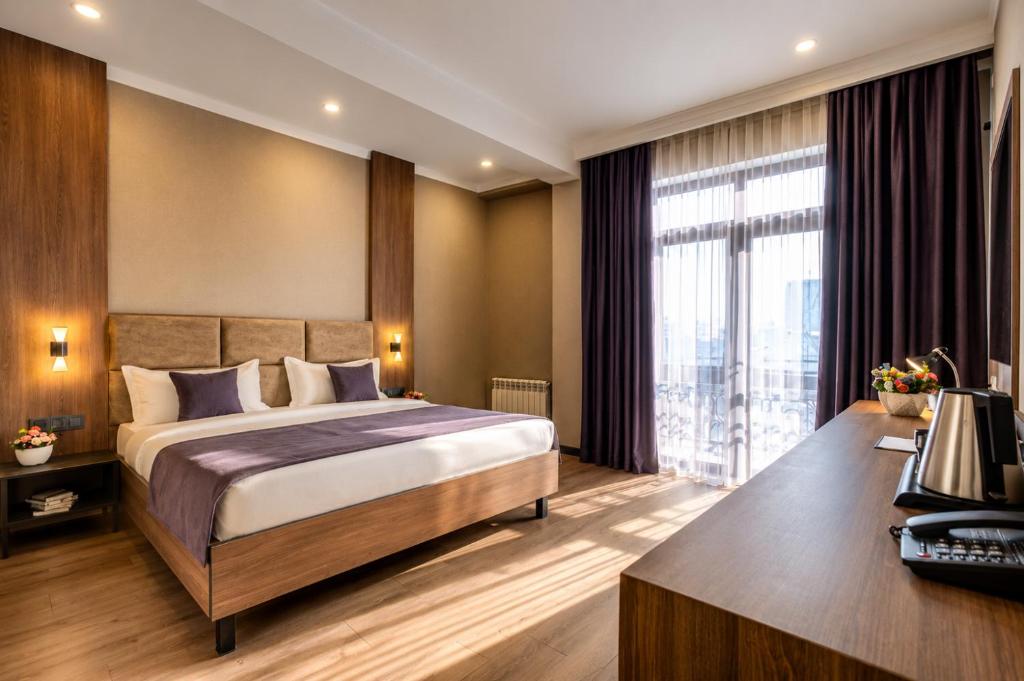 a hotel room with a bed and a desk at Sara Hotel Bishkek in Bishkek