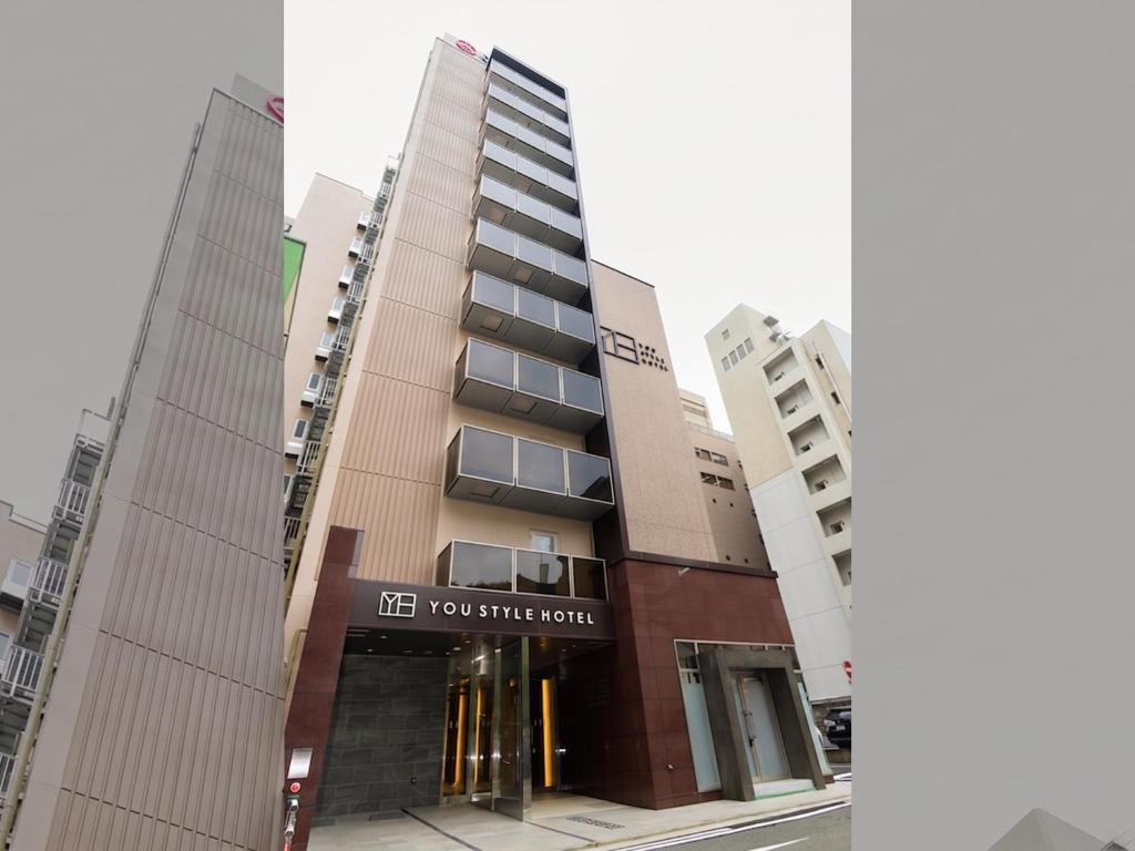 a tall building with a sign in front of it at YOU STYLE HOTEL HAKATA in Fukuoka
