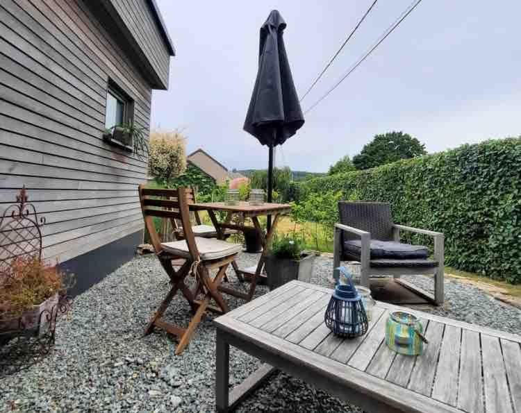 a patio with a table and chairs and an umbrella at Au doux gîte in Bras-Haut