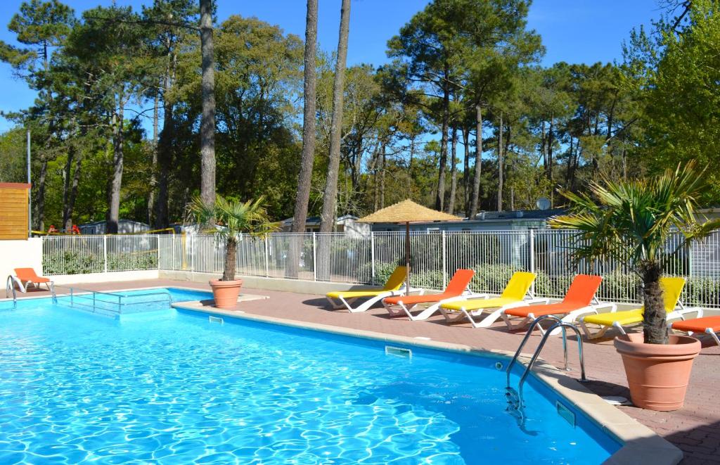 - une piscine avec des chaises longues et des parasols dans l'établissement Camping Le Clos Des Pins, à Longeville-sur-Mer