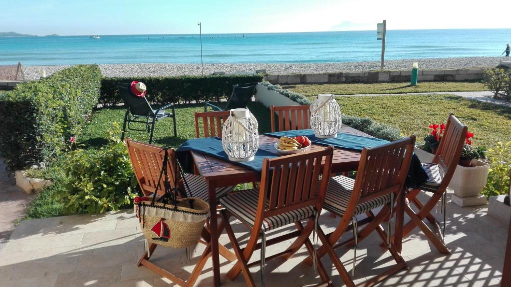 Apt playa de Muro ca n Ines - 1ª linea de playa في بورت ذالكوذيا: طاولة خشبية بأربعة كراسي والمحيط في الخلفية