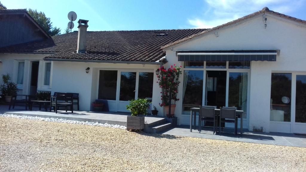 a white house with a table and chairs in front of it at Le Bois Du Mas in Saint-Aulaye