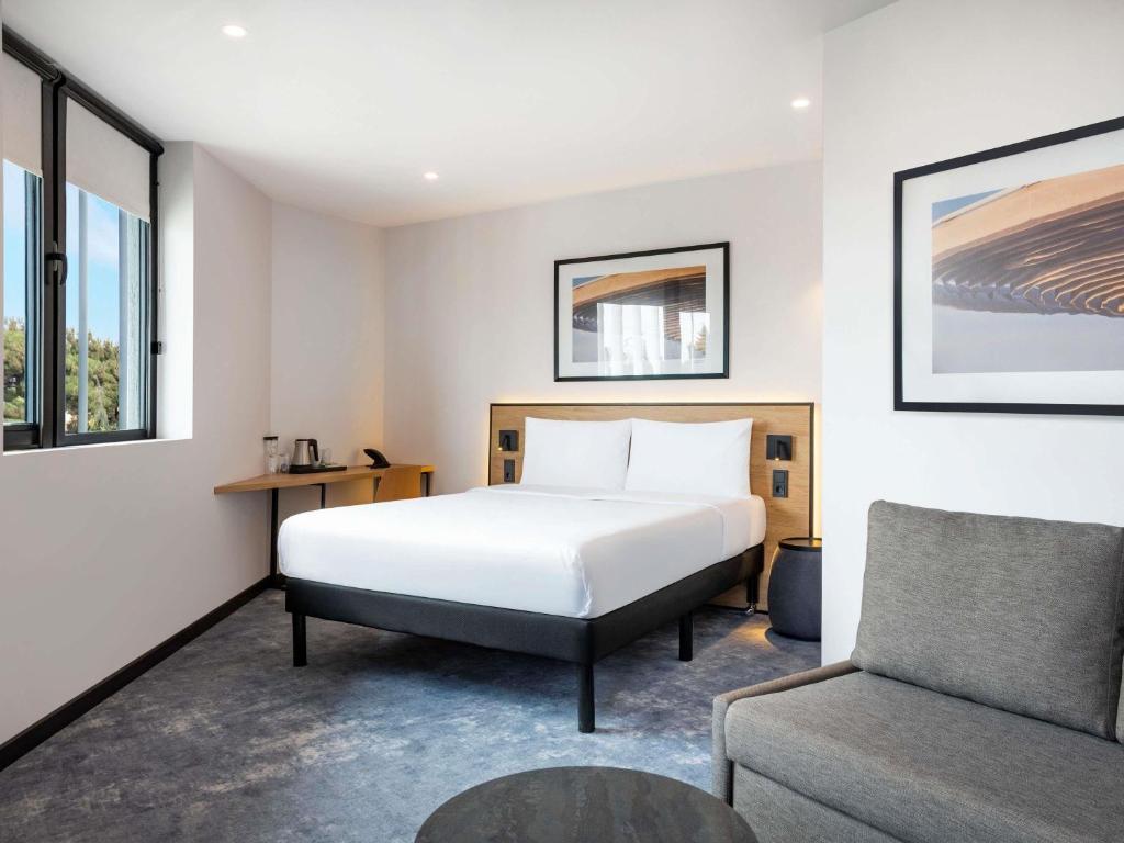 a hotel room with a bed and a chair at ibis Tbilisi Airport in Tbilisi City