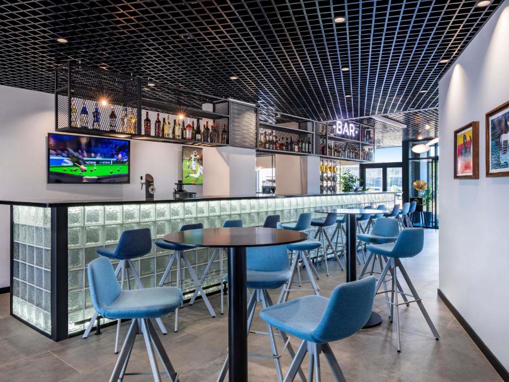 a bar with blue chairs and tables in a restaurant at ibis Tbilisi Airport in Tbilisi City