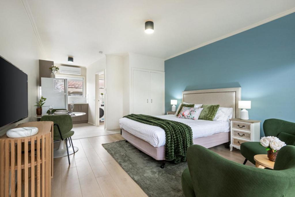 a bedroom with a bed and a living room with chairs at Newly Renovated Geelong Serviced Apartments by Short & Long Stays in Geelong