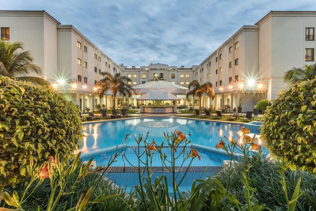 Hotel Vip Grand Maputo في مابوتو: فندق فيه مسبح كبير امام مبنى
