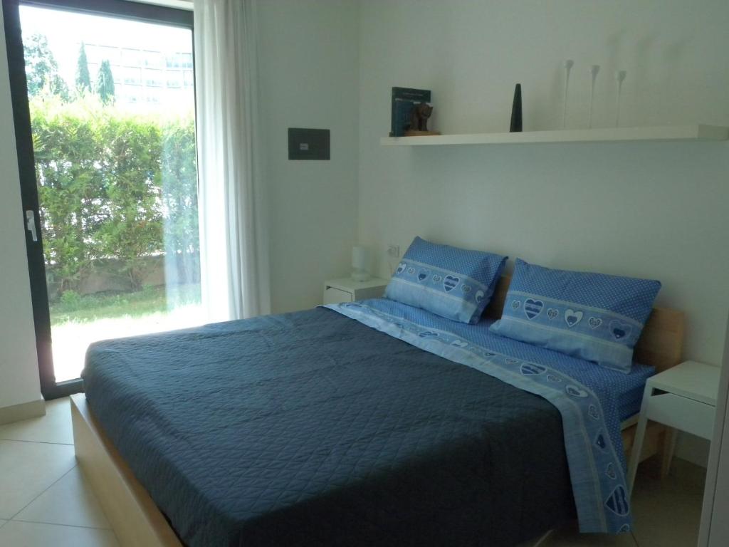 リーヴァ・デル・ガルダにあるSole Riva apartmentのベッドルーム1室(青い枕のベッド1台、窓付)