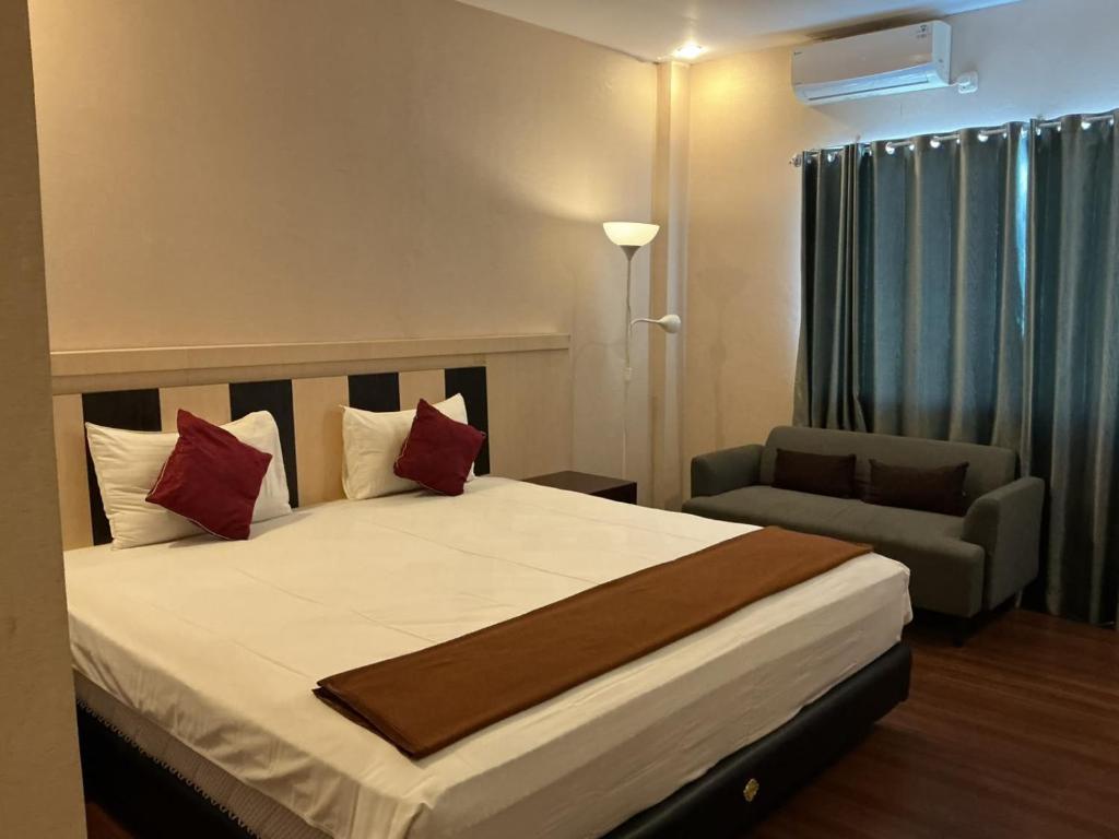 a bedroom with a large bed and a chair at Grand Duta Hotel in Palu