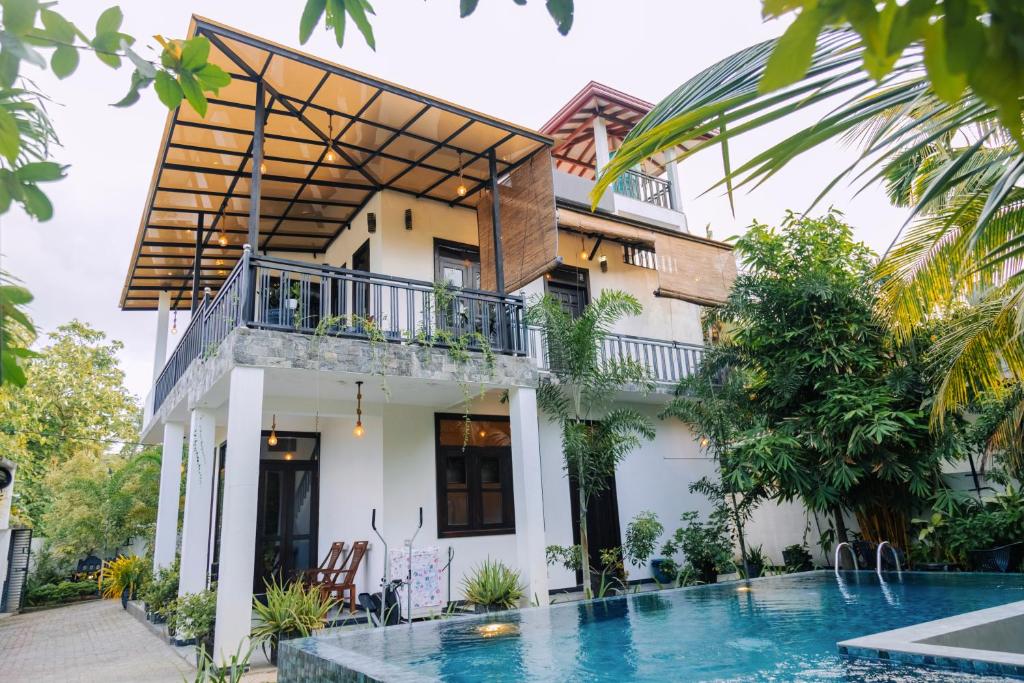 a villa with a swimming pool in front of a house at Meadow View Villa in Dickwella