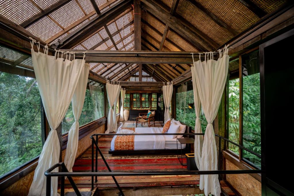 a bedroom in a tree house with a bed and curtains at Kalpa House Sidemen in Sidemen