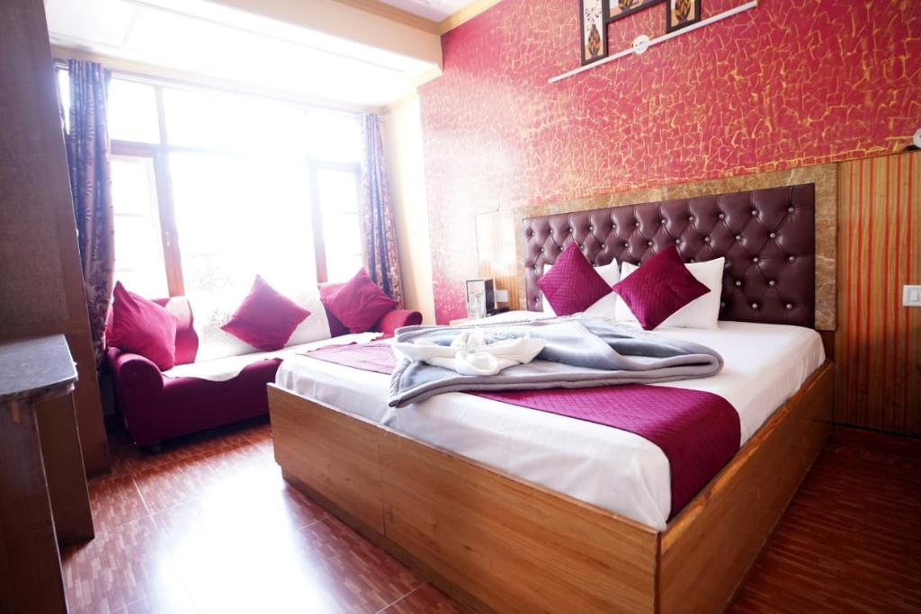 a bedroom with a large bed with purple pillows at Hotel King Palace in Shimla