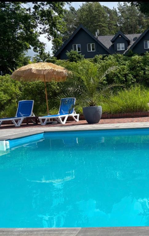 two chairs and an umbrella next to a swimming pool at Las,Jezioro,Masaże,SPA in Ostrzyce