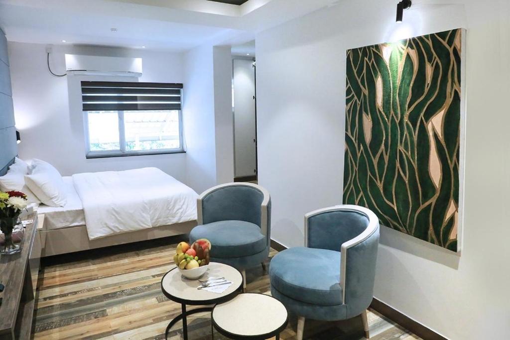 a room with a bed and two chairs and a table at Sri Suryas Hotel in Colombo