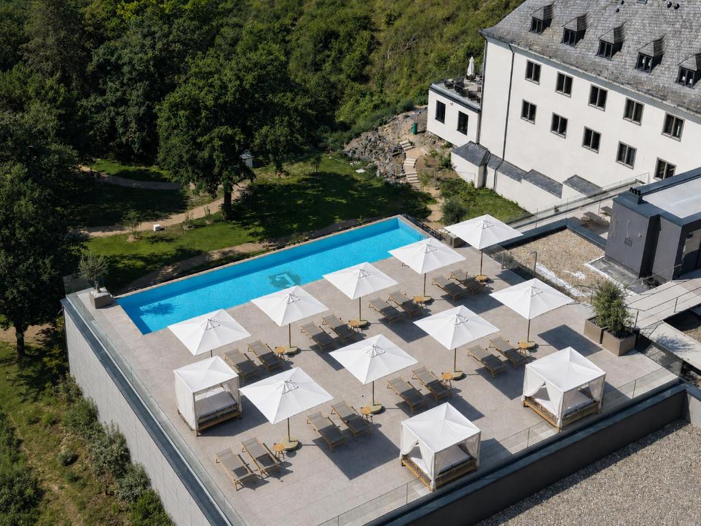 an overhead view of a pool with tables and white umbrellas at Jakobsberg Nature Resort - Hotel & Golf in Boppard