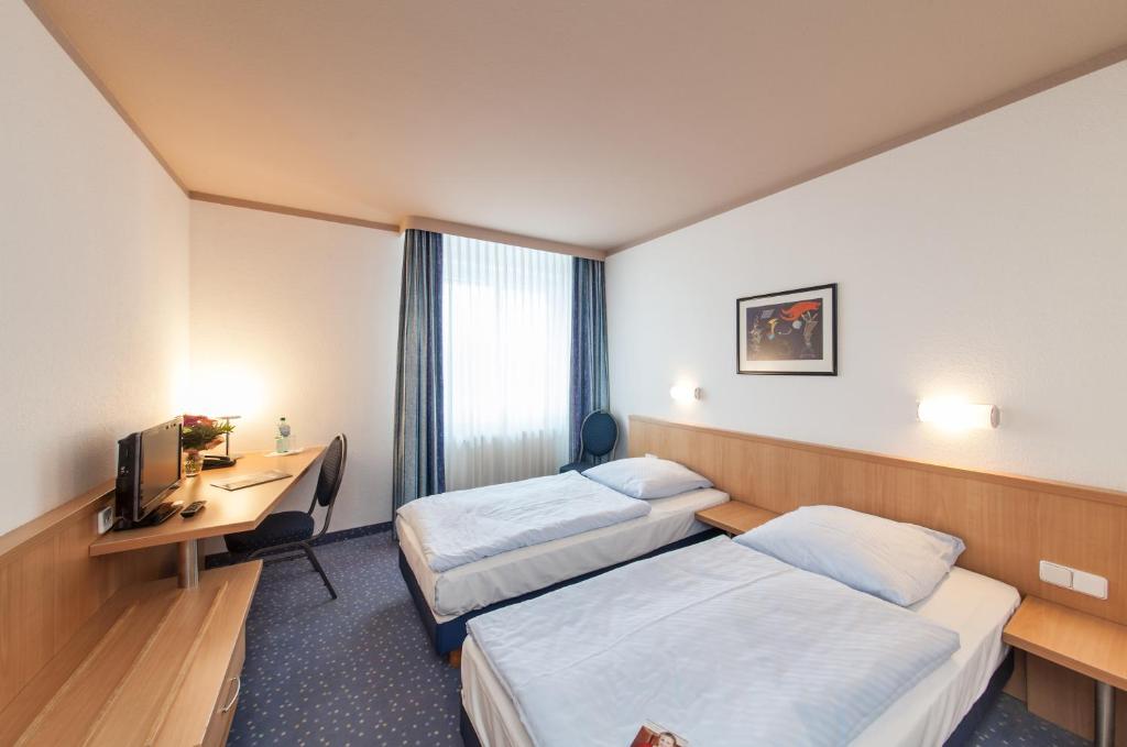 コトブスにあるNovum Hotel Seegraben Cottbusのベッド2台とデスクが備わるホテルルームです。