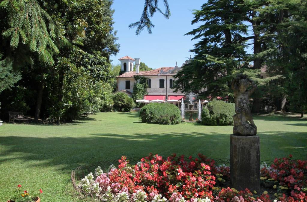 een tuin met bloemen en een huis op de achtergrond bij Hotel Villa Luppis in Pasiano di Pordenone