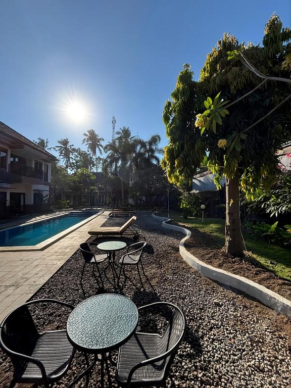 a patio with tables and chairs next to a pool at Melati Kuta Lombok in Kuta Lombok