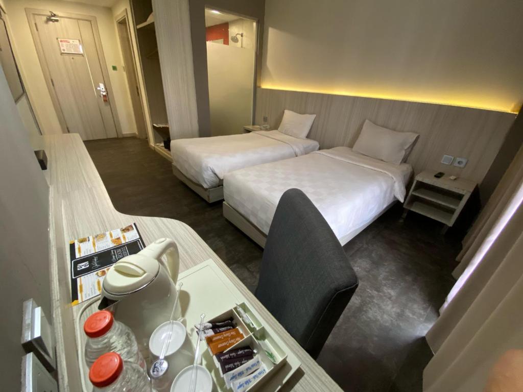a hotel room with two beds and a table at Grand Kolopaking Hotel in Kebumen