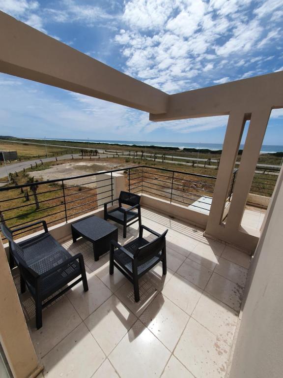 a balcony with chairs and tables and a view of the ocean at la vue coucher de soleil in Hauara