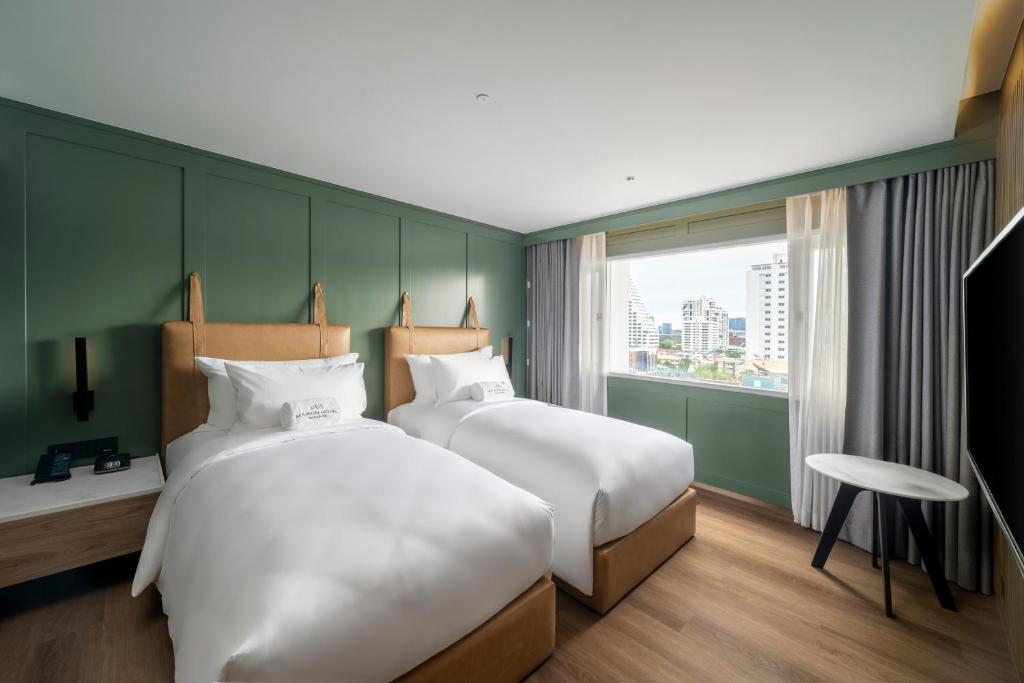 A twin room with two separate beds and a bright urban window view.