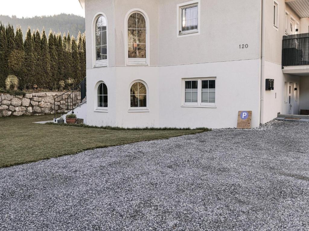 a large white house with a gravel driveway at Modern apartment in Seefeld in Reith bei Seefeld
