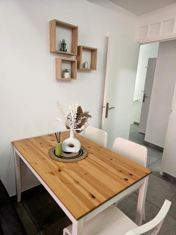 a wooden table with white chairs and a vase on it at Cozy haven in Venise Provençale in Martigues