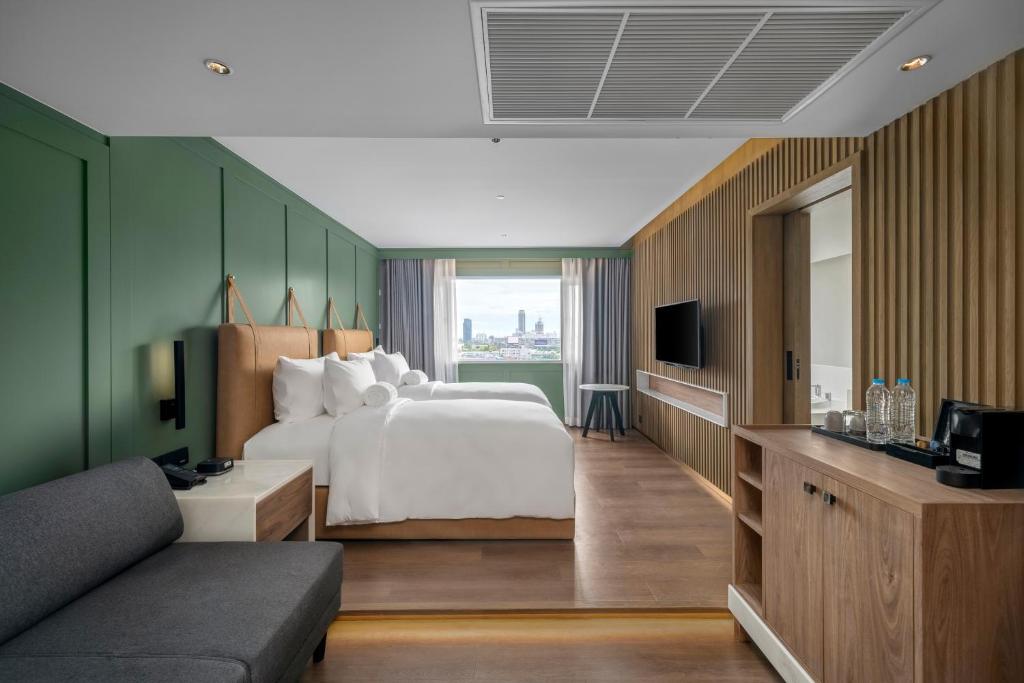 A twin room viewed from the sitting area, with a city window and minibar cabinetry.
