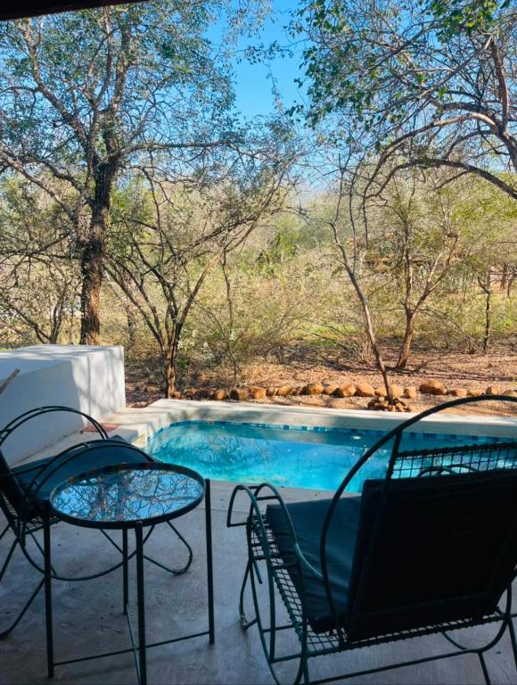 a patio with two chairs and a swimming pool at Bushbuck Rest in Marloth Park