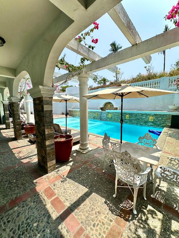 an outdoor patio with umbrellas and a swimming pool at Casa Del Faro in Puerto Galera