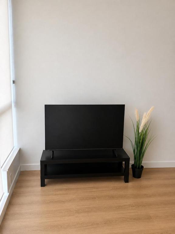 a black bench in a white room with a plant at Morden suite in Surrey