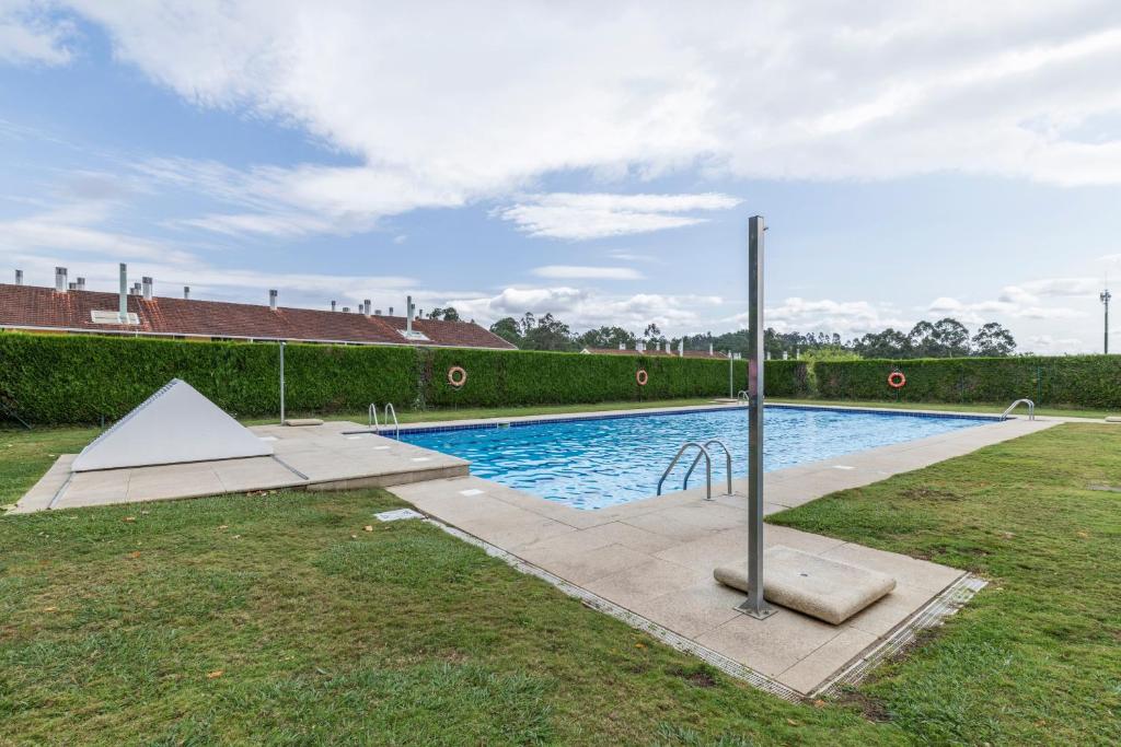 ein Swimmingpool in einem Garten neben einer Hecke in der Unterkunft Apartamento Morriña in Brion