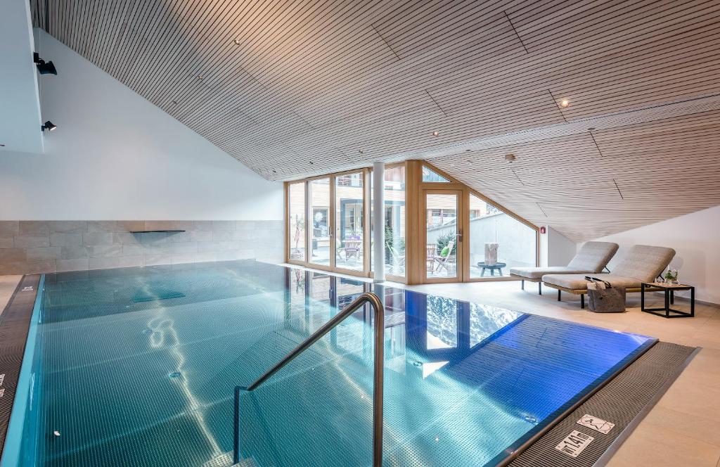 a swimming pool in a house with a large ceiling at Hotel Stäfeli in Lech am Arlberg