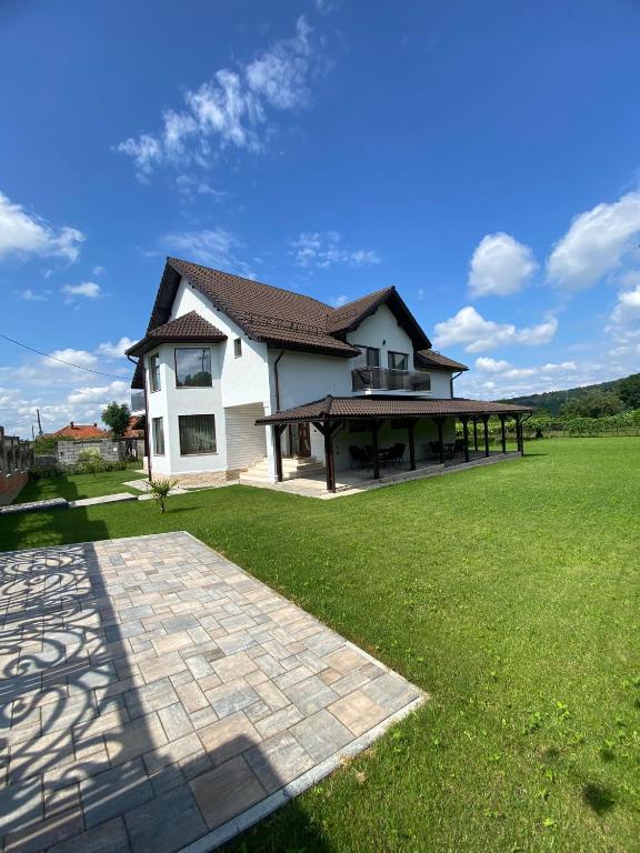 a house with a large yard with a green lawn at Alpine Grace Retreat in Novaci-Străini