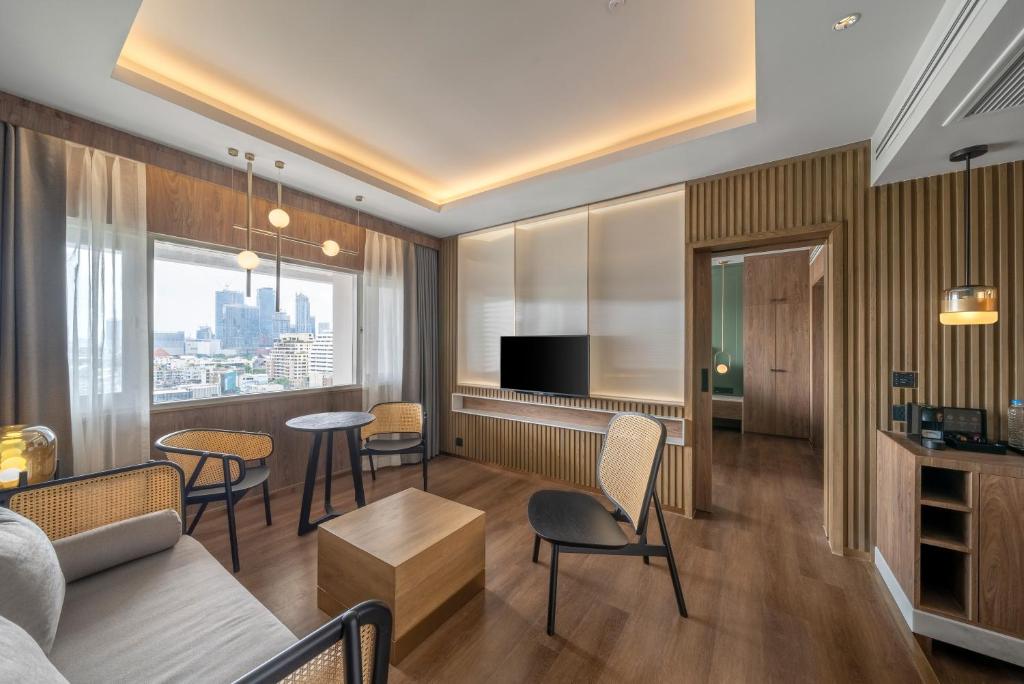 A living room with a sofa, television, city outlook and visible minibar or storage cabinetry.