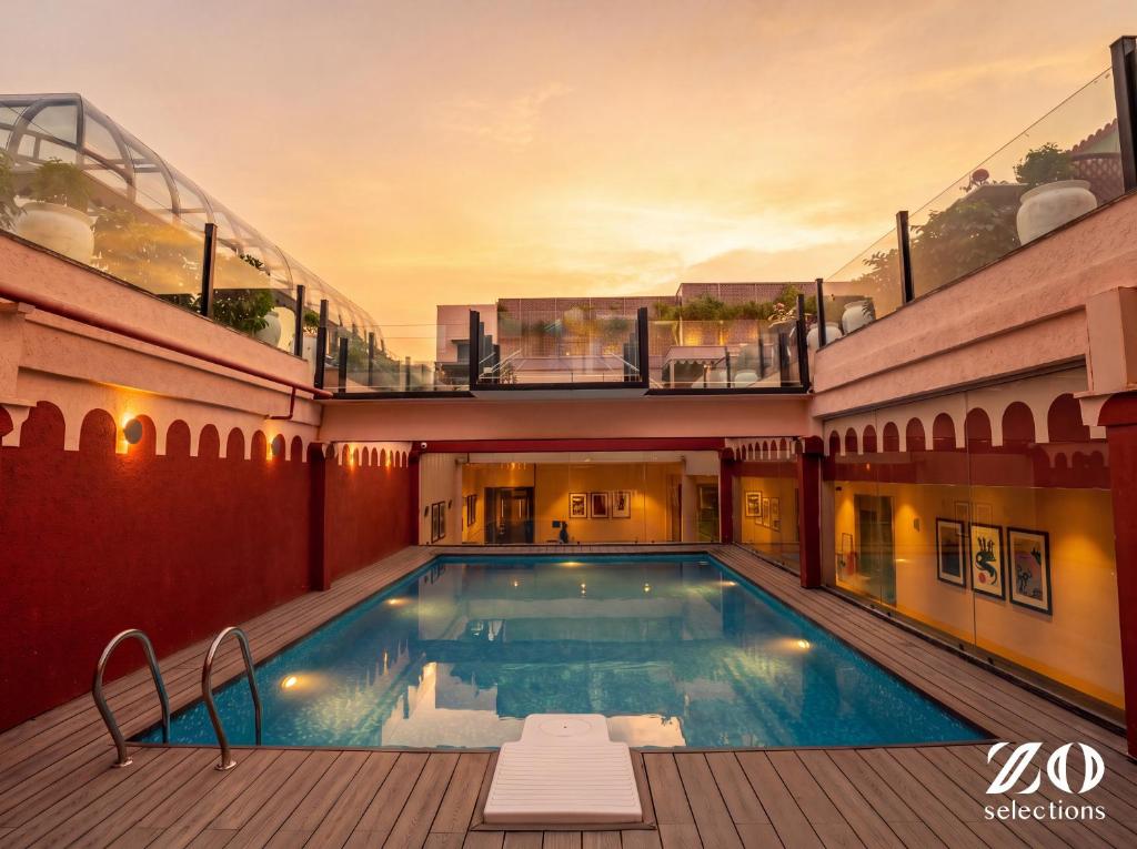 a large swimming pool in a building with a balcony at Zo Selections Jaipur by Zostel in Jaipur