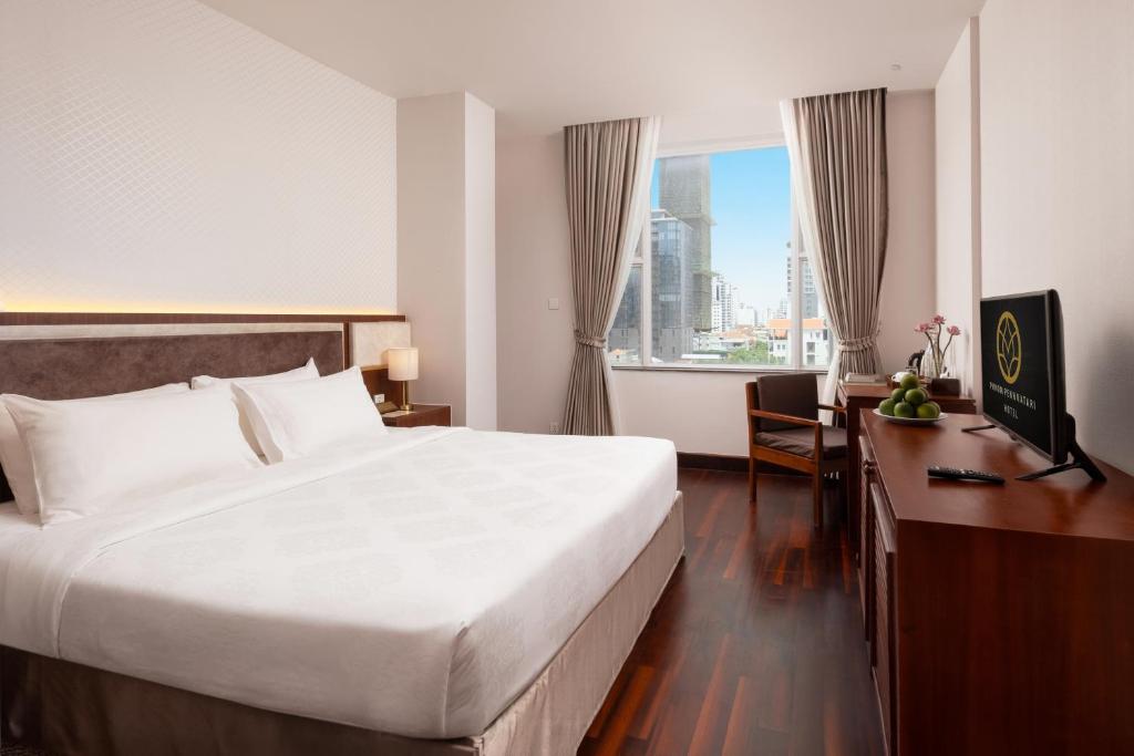 a hotel room with a bed and a desk and a window at Phnom Penh Katari Hotel in Phnom Penh