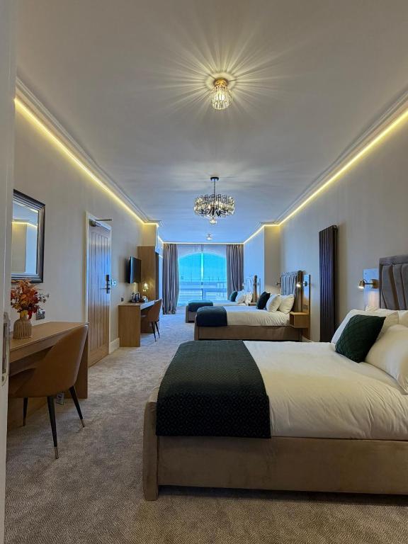 a hotel room with two beds and a desk at Emerald Tide Hotel - Blackpool in Blackpool
