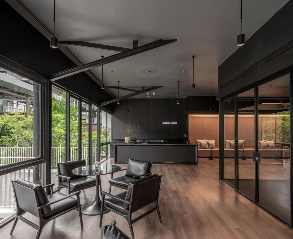 A dark, contemporary lounge with armchairs, a reception desk, and tall windows.